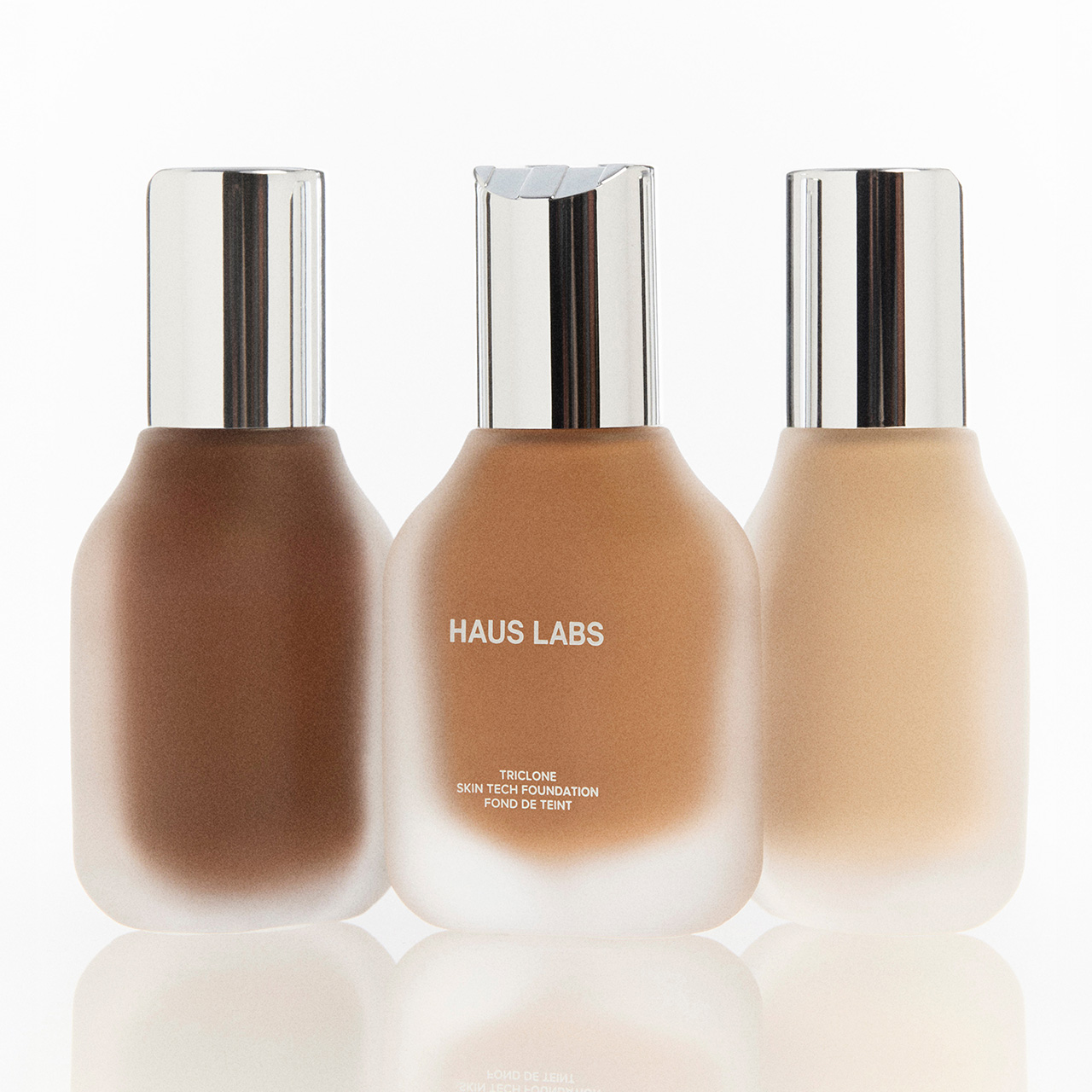 Three bottles of Haus Labs Triclone Skin Tech Foundation in varying shades from deep to light, displayed against a white background