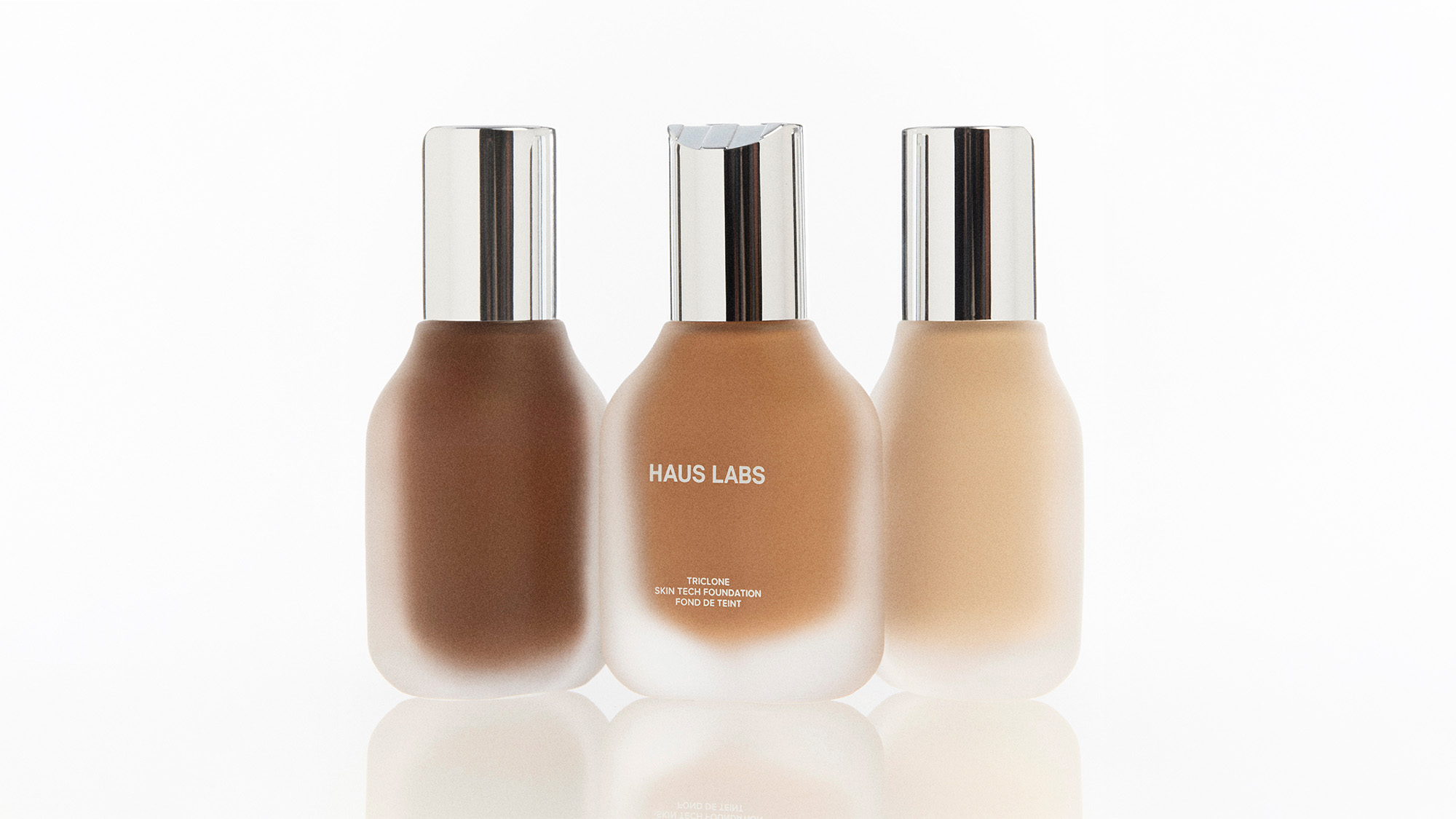Three bottles of Haus Labs Triclone Skin Tech Foundation in varying shades from deep to light, displayed against a white background