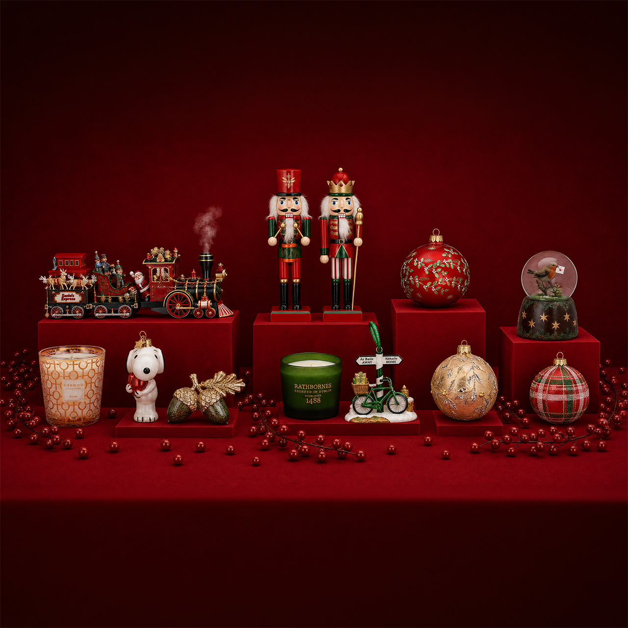 Christmas decorations collection including toy train, nutcrackers, candles, baubles, and snow globe on red display