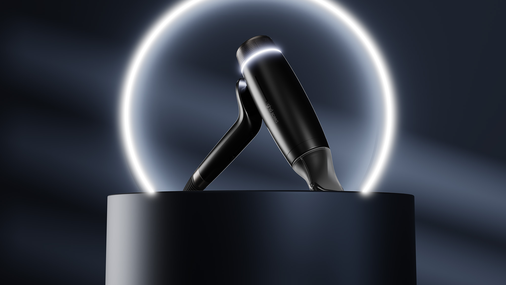 A black futuristic device is displayed on a pedestal, illuminated by a glowing circle in a dark setting.