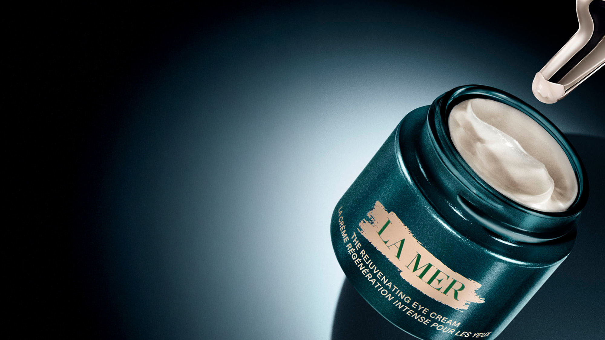 A jar of La Mer eye cream with an applicator, containing a light cream product.