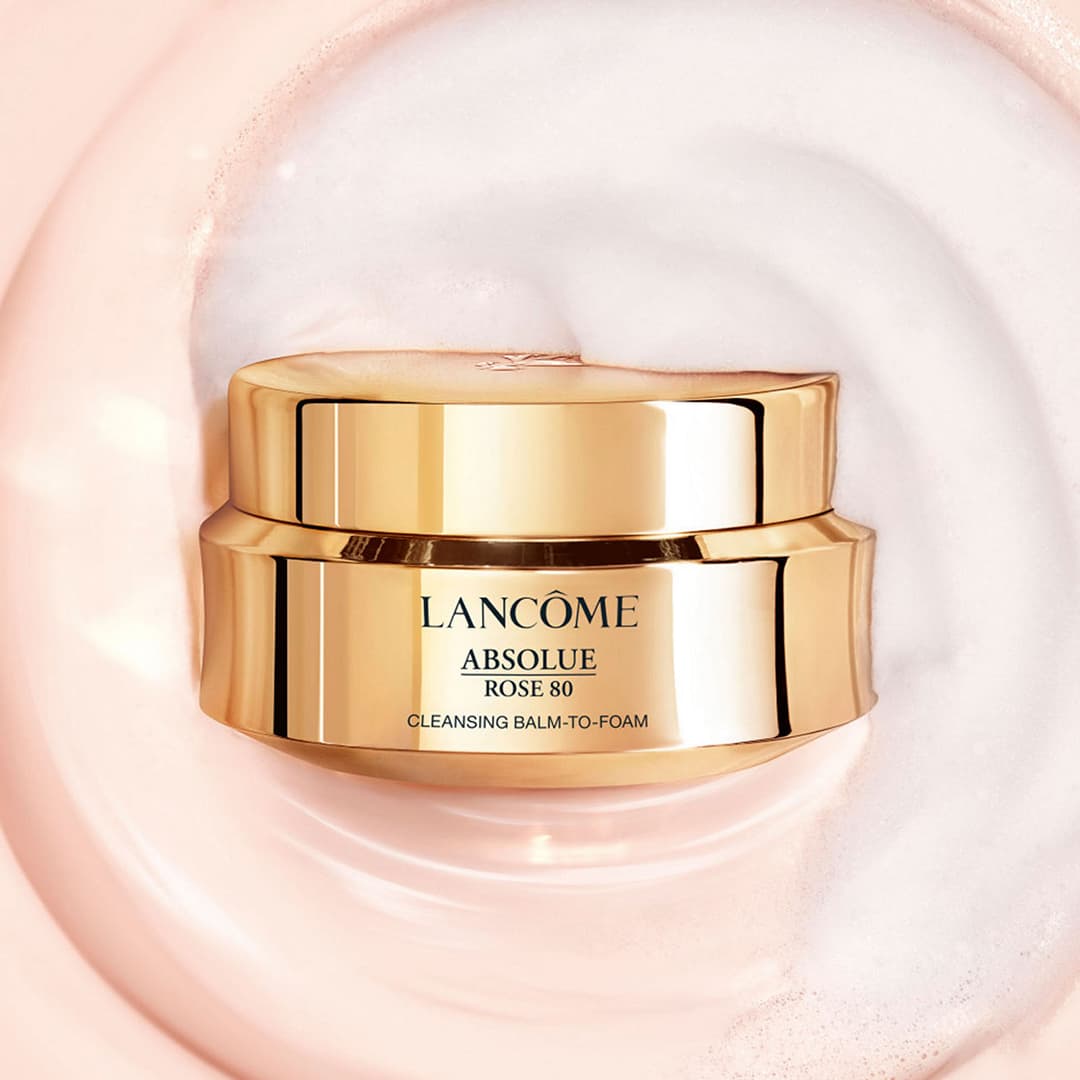 Shop Cleansers with a gold jar of Lancôme Absolue Cleansing Balm-to-Foam on a textured pink and white background.