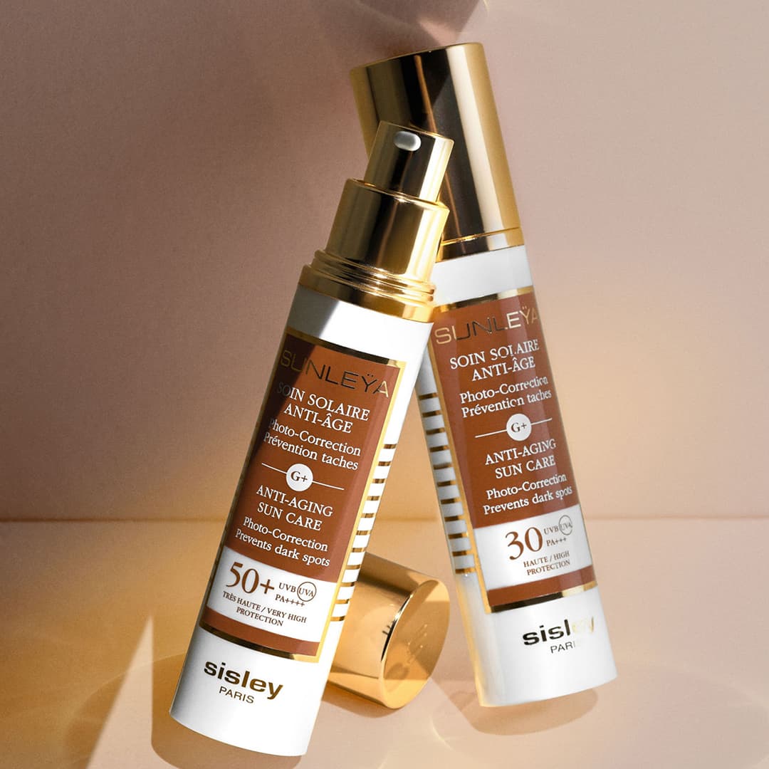 Shop SPF & Sun Care with two bottles of Sisley Paris anti-aging sun care products with SPF 50+ and 30 displayed on a beige background.
