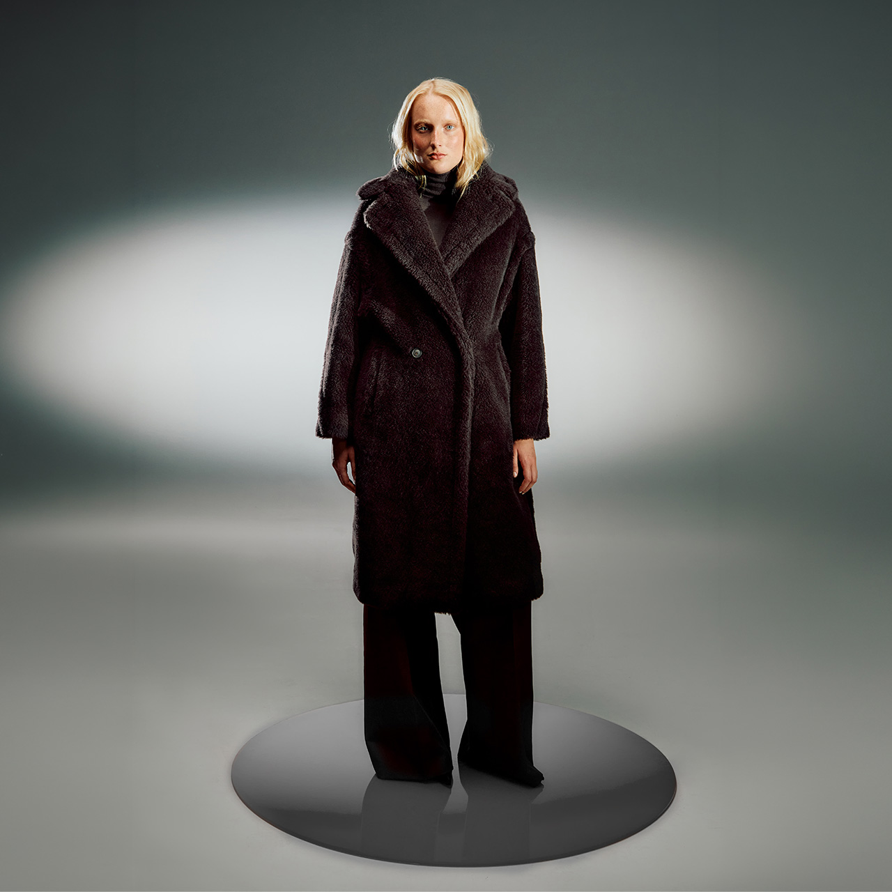 Woman wearing dark burgundy textured coat with oversized collar and wide leg trousers