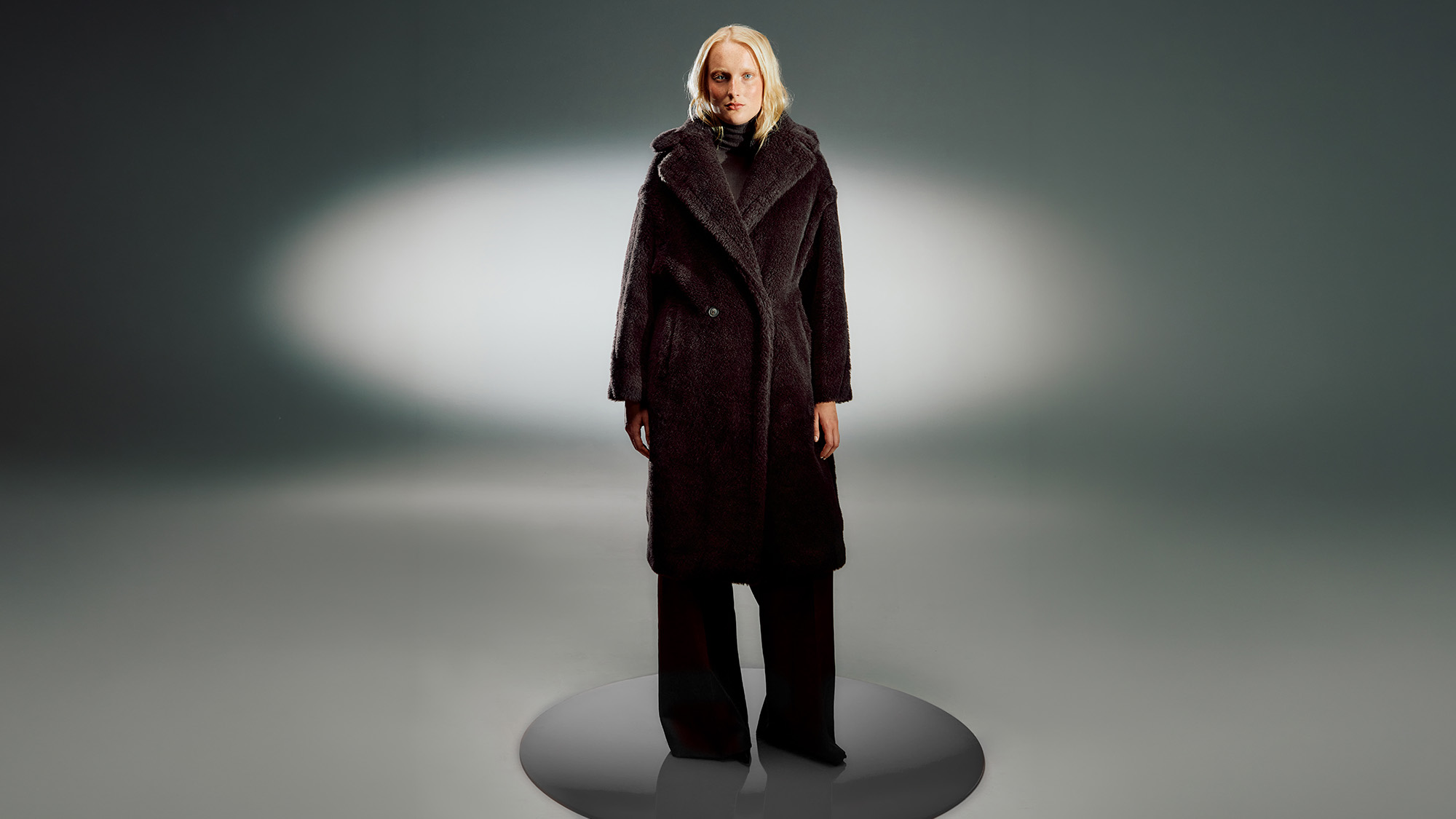Woman wearing dark burgundy textured coat with oversized collar and wide leg trousers