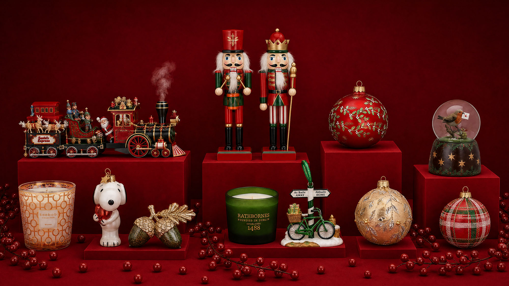 Christmas decorations including nutcrackers, festive baubles, decorative train set, snow globe, candle, and Rathbornes candle on red platform