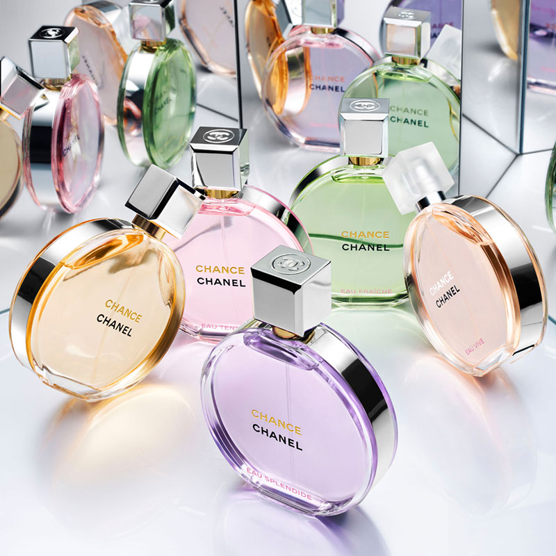 Chanel beauty perfumes in pastel colors are arranged with mirrored reflections.