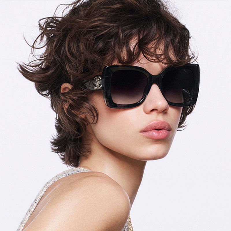 Person wearing large Chanel sunglasses with dark lenses and a black frame.