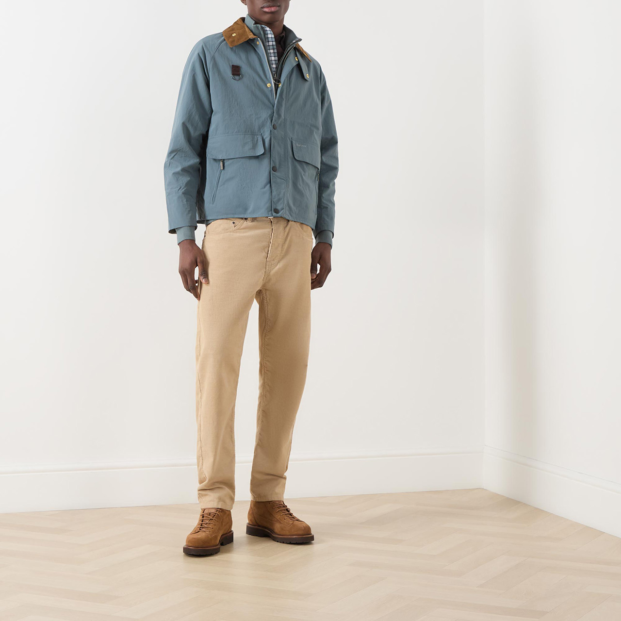 Menswear model wearing blue Barbour wax jacket with contrast collar, and brown trousers