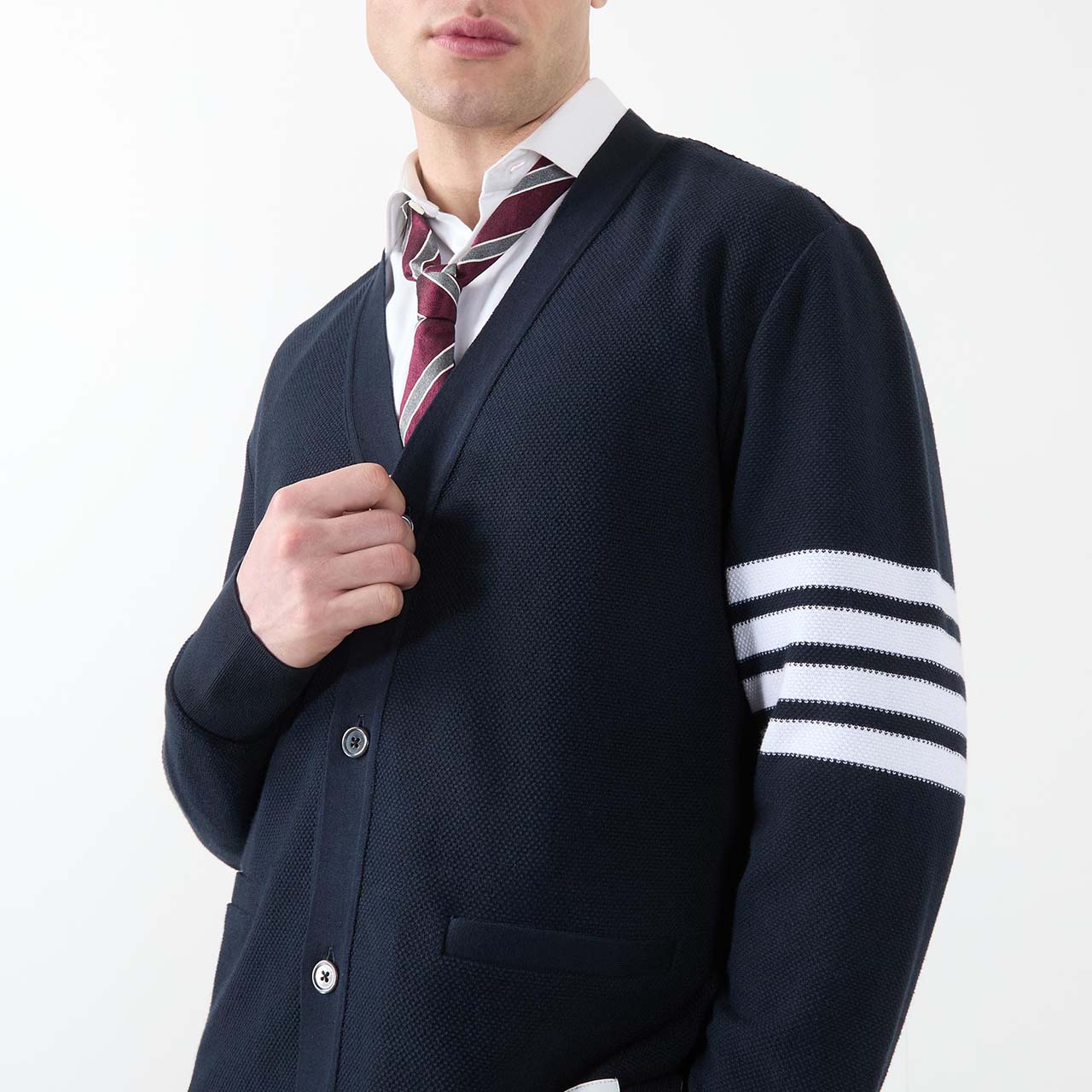Menswear model wearing button up collegiate knitted cardigan, with a striped tie