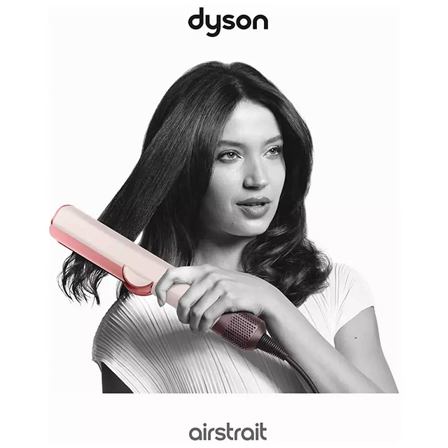 A woman uses a Dyson Airstrait hair styling tool on her hair.