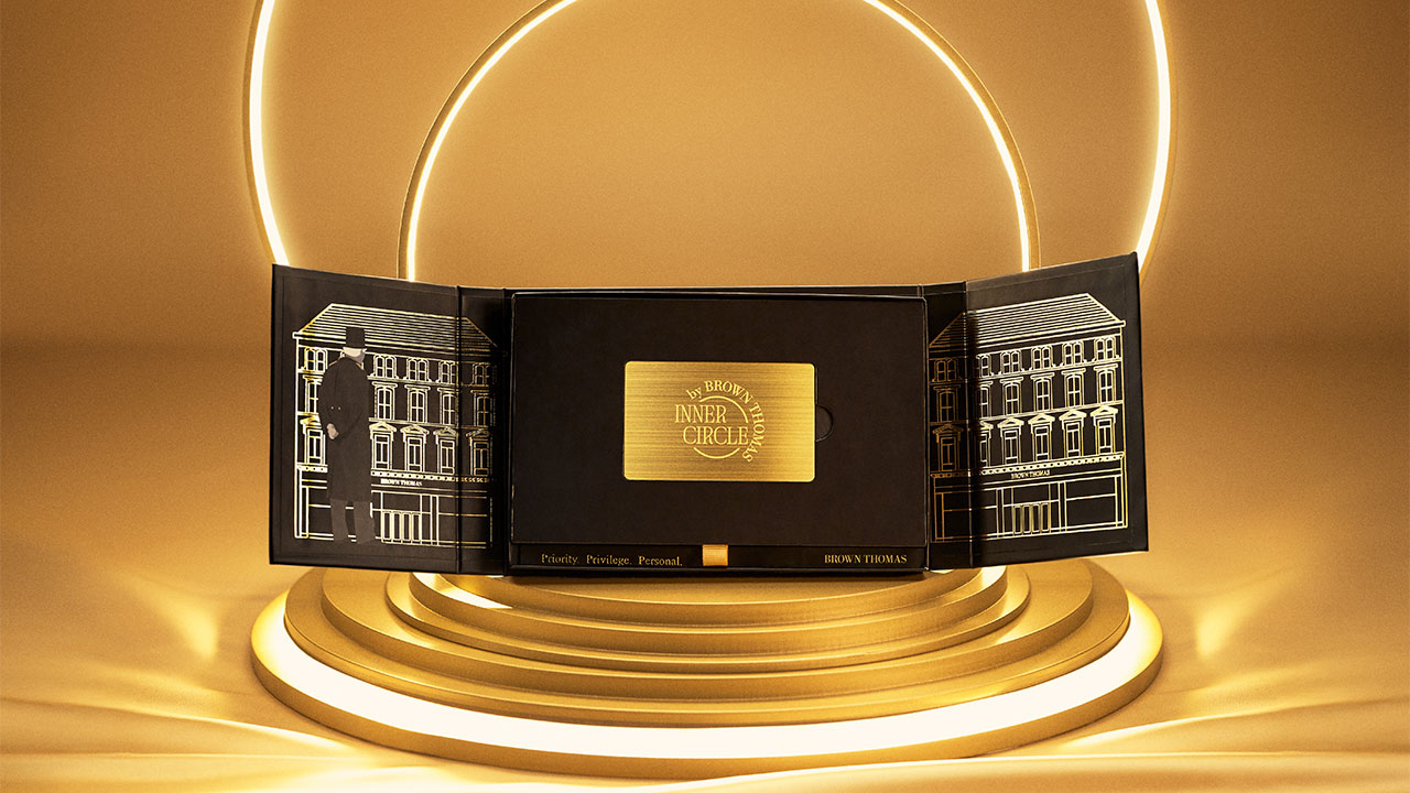 A golden Inner Circle membership card titled is displayed in an elegant black and gold package with architectural sketches, set against glowing rings.