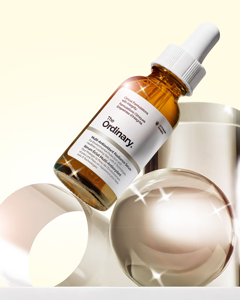 
A brown bottle of 'The Ordinary' skincare serum is displayed, surrounded by reflective spheres and a light background.


