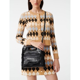 Model carrying Maje Mcroc-Embossed Leather Bag in black with croc texture, fringe sides and gold logo detail, styled with argyle knit co-ord