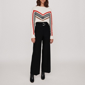 Model wearing Maje Parc Wide Leg Trousers in black with silver-tone D-ring belt, styled with a chevron-stripe knit and black ankle boots
