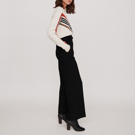 Model wearing Maje Parc Wide Leg Trousers in black with wide silhouette, styled with a striped cream knit and black ankle boots