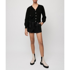 Model wearing Maje Mistral Jewel Button Cardigan in black with jewel buttons, styled with black leather shorts and cream chelsea boots