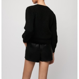 Model wearing Maje Mistral Jewel Button Cardigan in black, V-neck with long loose sleeves, styled with black leather shorts. Rear view
