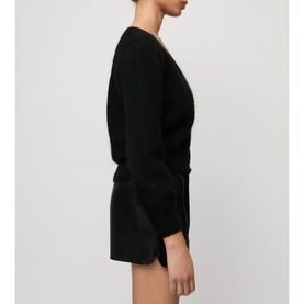 Model wearing Maje Mistral Jewel Button Cardigan in black, V-neck, long sleeves with cuffs, styled with black mini shorts