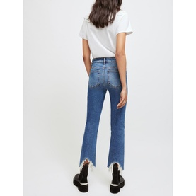 Model wearing Maje Pachabfran Mid-Rise Slim Ripped Jeans in blue denim with frayed hem, styled with white tee and black shoes