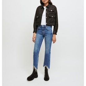Model wearing Maje Pachabfran Mid-Rise Slim Ripped Hem Jeans in blue with ripped hem, styled with black tweed jacket and ankle boots