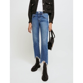 Model wearing Maje Pachabfran Mid-Rise Slim Ripped Hem Jeans in blue denim, styled with a black sequin jacket and black Chelsea boots