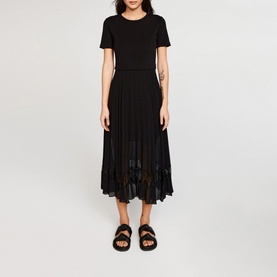 Model wearing Claude Pierlot Teli Pleated Midi Dress in black, short sleeves, pleated chiffon skirt, styled with black flat sandals