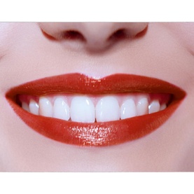 Model wearing Armani Beauty Ecstasy Shine Lipstick in a vivid red shade, shown close up with a bright smile and glossy finish