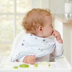 Baby wearing Aden & Anais Two Pack Burpy Bibs in grey with star print, seated in highchair with food pieces on tray