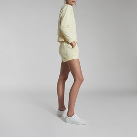 Model wearing Reiss Annie Jersey Shorts in yellow, styled with matching yellow sweatshirt and white trainers