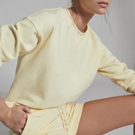 Model wearing Reiss Annie Jersey Shorts in yellow, styled with a matching yellow sweatshirt