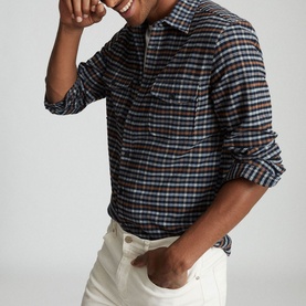 Model wearing Reiss Ash Overshirt in blue check, styled with white trousers. Long-sleeved pullover with chest pocket