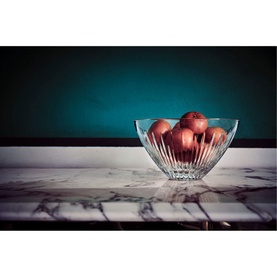 Waterford Mara Bowl 9in in clear crystal with vertical cut detailing, styled on marble surface with red apples, teal backdrop