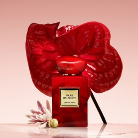 Armani Beauty Rouge Malachite Eau de Parfum in red bottle with gold label, styled with red anthurium flower and white bloom