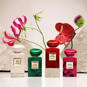 Armani Beauty Rouge Malachite Eau de Parfum shown alongside three other fragrances from the collection, styled with tropical flowers and stone props