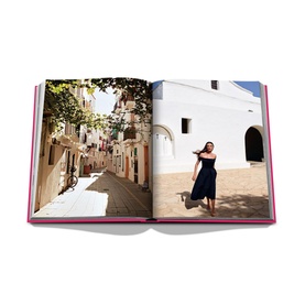 Assouline Ibiza Bohemia hardbound book open to spread showing colourful village street and woman in navy dress beside white building