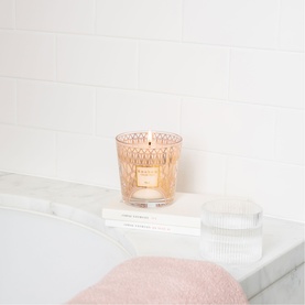 BAOBAB My First Baobab Paris candle in amber textured glass vessel, styled on marble bath tray with pink towel and ribbed glass dish