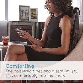 Model with Homedics Shiatsu Pro Back Massage Chair, dark upholstery with bolstered sides, using remote control while seated