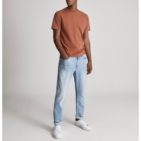 Model wearing Reiss Bless Regular Fit T-Shirt in brown with round neckline, styled with light wash jeans and white trainers