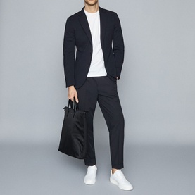 Model wearing Reiss Bless Regular Fit T-Shirt in white, styled with dark blazer, tapered trousers, and white trainers, carrying black tote bag