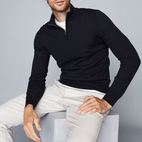 Model wearing Reiss Blackhall Funnel Neck Sweater in blue with half-zip detail, styled with white T-shirt and light grey trousers