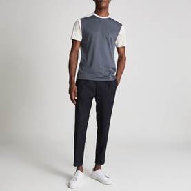 Model wearing Reiss Brighton Pleat Front Trousers in blue, styled with a grey colour-block T-shirt and white trainers