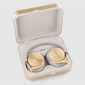 Bang & Olufsen Beoplay H95 wireless headphones in gold, shown folded inside cream luxury travel case