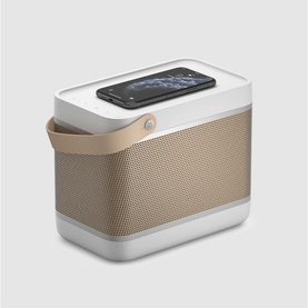 Bang & Olufsen Beolit 20 portable Bluetooth speaker in grey with tan fabric grille, leather handle, and wireless charging pad on top
