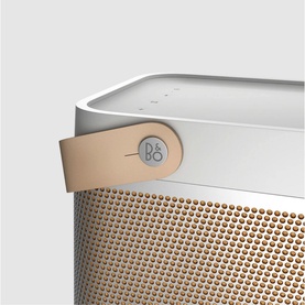 Bang & Olufsen Beolit 20 portable speaker in grey, close-up of gold mesh grille, tan leather carry strap and logo detail