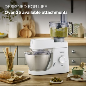 Kenwood stand mixer in white with stainless steel bowl and food processor attachment, styled in a kitchen setting with bread and olives