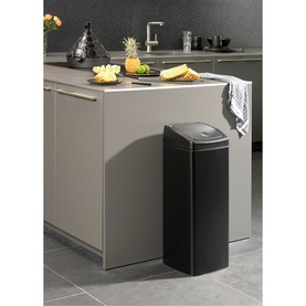 Brabantia Touch Rectangular Bin in black, shown beside a kitchen island with fruit and cutting board styled in background