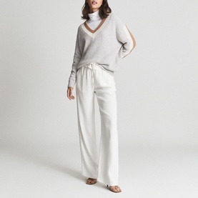Model wearing Reiss Cora Colour Block Cricket Sweater in grey with contrast V-neckline trim, styled with wide-leg cream trousers