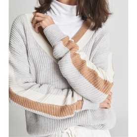Model wearing Reiss Cora Colour Block Cricket Sweater in grey with camel and cream stripe detail, styled with a white turtleneck underneath
