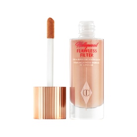 Charlotte Tilbury Hollywood Flawless Filter liquid highlighter in peach-nude tone, shown with applicator wand and rose gold cap